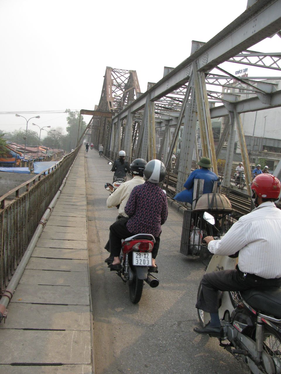 Lối đi trên Cầu Long Biên với xe máy và người qua lại sát khung thép.