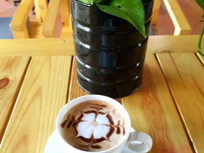 Ly cappuccino vẽ hoa trên bàn gỗ tại 33 Burger