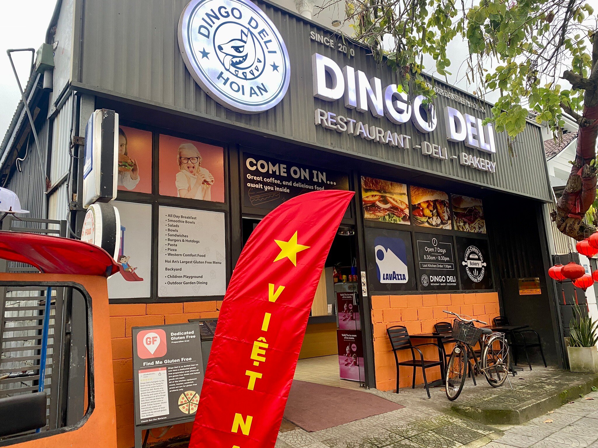 Mặt tiền Dingo Deli Hội An với logo chú chó dingo, bảng nhóm món và bàn ghế ngoài hiên