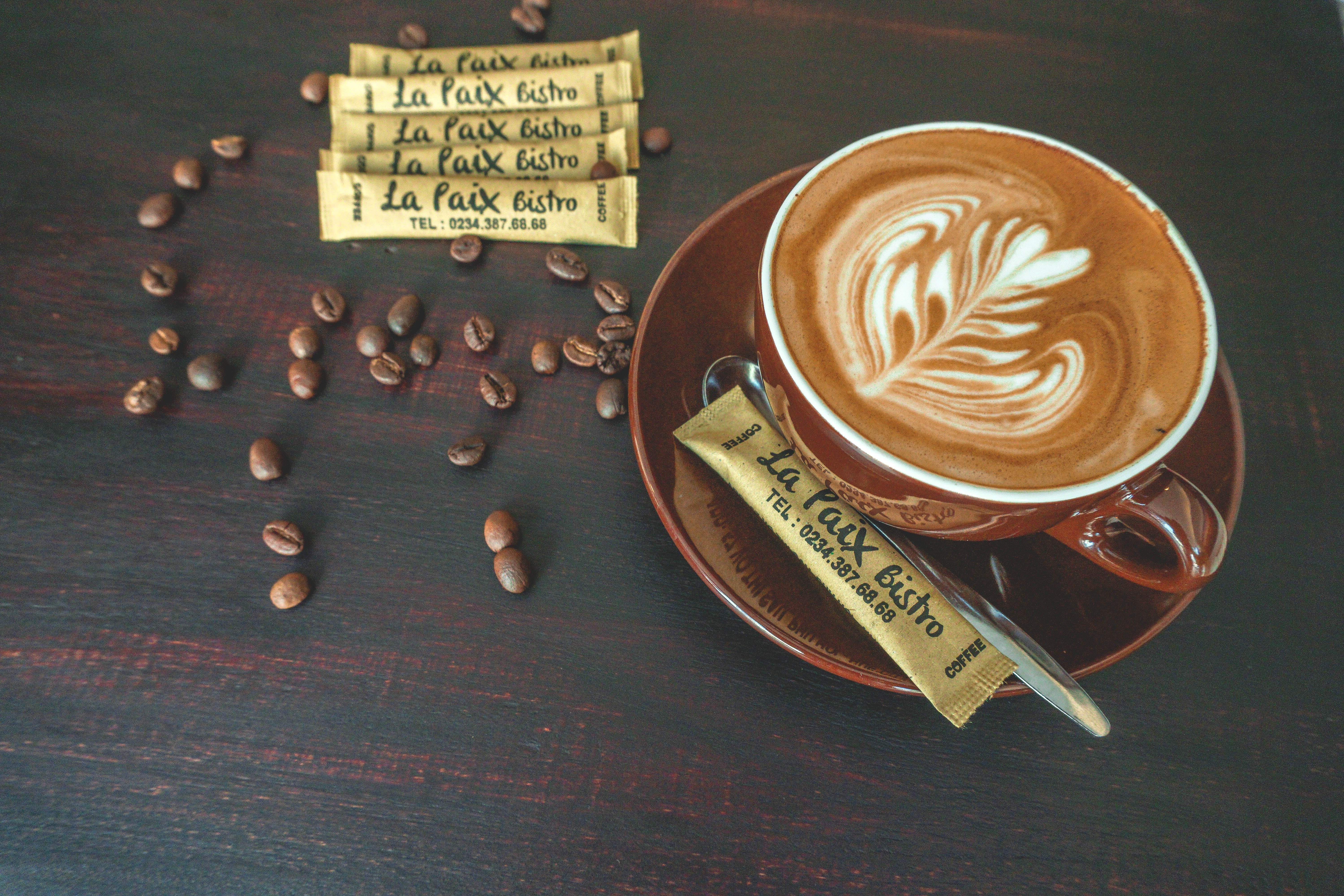 Tách cappuccino vẽ hình lá cùng gói đường in tên La Paix Bistro