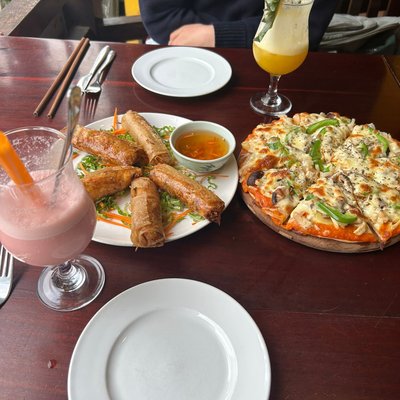 Chả giò, pizza rau củ và sinh tố trên bàn tại Ladybird Sapa Restaurant & Cafe
