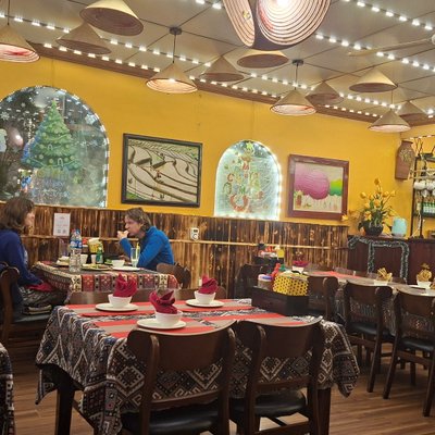 Phòng ăn tường vàng, đèn mây tre và bàn trải khăn thổ cẩm tại Little Vietnam Restaurant