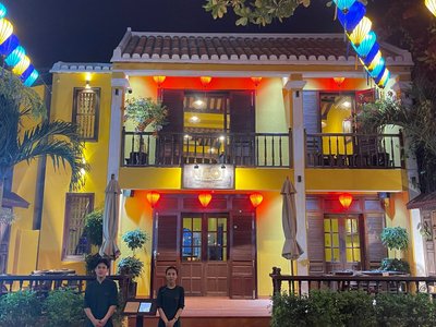 Mặt tiền nhà hai tầng tường vàng của Ngói Vietnamese Cuisine vào buổi tối
