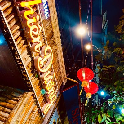 Biển hiệu đèn chữ Thiên Đường và đèn lồng đỏ trên mặt tiền tre của Nhà Hàng 7th Heaven