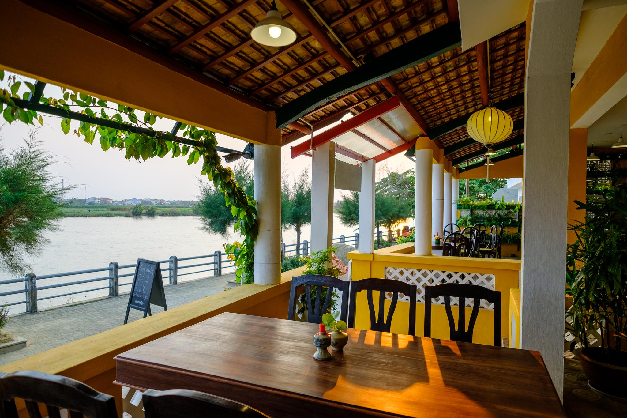 Bàn gỗ trên hiên nhà hàng Hoa Hiên nhìn ra sông lúc chiều