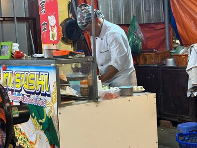 Xe quầy Ni Sushi Japanese Street Food với bảng hiệu vàng và đầu bếp áo trắng ở Hội An