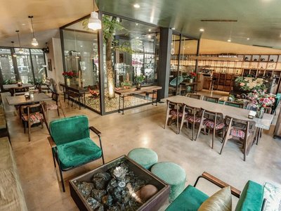 Góc ngồi ghế nhung xanh, vườn kính nhỏ và bàn dài trong Pizza Goong Hạ Long