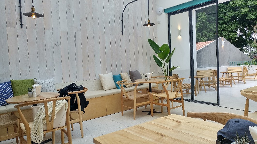 Khu ngồi với ghế gỗ, băng ghế gối tựa và cửa kính mở ra sân ngoài trời của Poke Hanoi.
