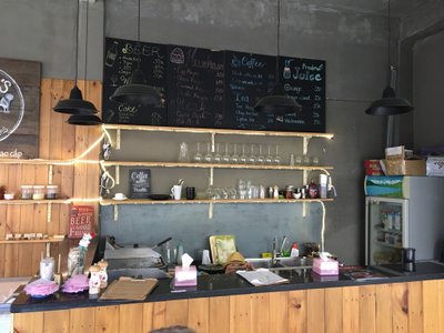 Quầy bar với bảng phấn đồ uống và kệ ly tại Capo's Đà Lạt