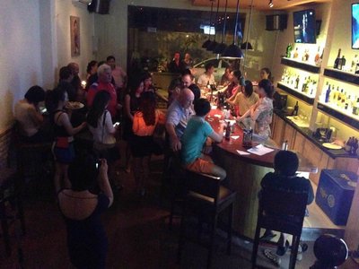 Quầy bar dài của Vertigo Bar Đà Nẵng với kệ rượu sáng đèn và khách ngồi kín quanh quầy